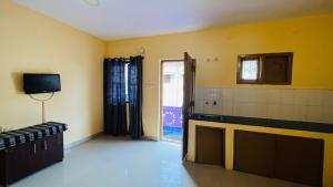 a room with a kitchen with yellow walls and a television at Hidden doors in Ooty