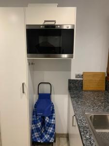 a small kitchen with a microwave and a blue suitcase at El Hogar de Belela in Oviedo