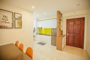 een keuken met een houten deur, een tafel en een koelkast bij Vân' House in Ha Long