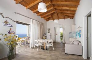 een woonkamer met een tafel en stoelen en de oceaan bij Ploes Villas in Skafidia