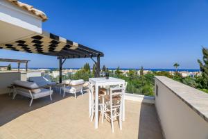 een patio met een tafel en stoelen en een parasol bij Villa Greco Mare #40 in Protaras