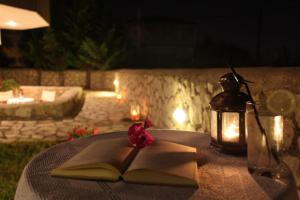 un libro abierto sobre una mesa con una linterna y una vela en Porto Nirikos, en Lefkada