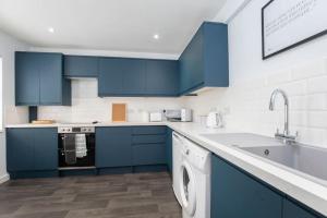 uma cozinha com armários azuis e uma máquina de lavar louça em The Races, Portland Place. em Cheltenham