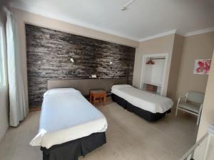 twee bedden in een kamer met een bakstenen muur bij Hostal Mar del Plata in El Arenal