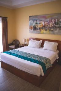 1 dormitorio con 1 cama grande y una pintura en la pared en Sastra Ubud House en Ubud