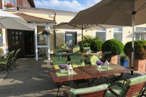 a patio with a wooden table and chairs and an umbrella at Landhotel Bergischer Hof GmbH Marialinden in Overath