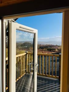 a door to a balcony with a view of the water at Hidden Hut - Aros View - Tobermory in Tobermory