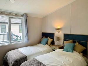 two beds in a room with a window at Springwood Holiday Park in Kelso