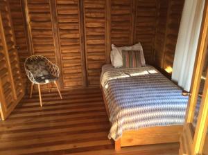 1 dormitorio con 1 cama y 1 silla en una habitación en Maison autonome en bois, à Brasilito, en Brasilito