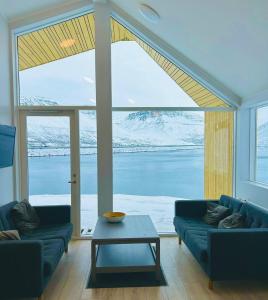 un soggiorno con divano blu e una grande finestra di Fisk Club Cottages a Suðureyri