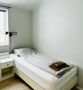 ein kleines Schlafzimmer mit einem Bett und einem Fenster in der Unterkunft Fisk Club Cottages in Suðureyri