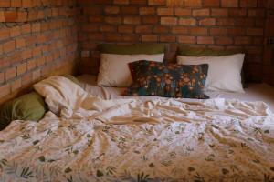an unmade bed in a room with a brick wall at hugs stay nam ban in Hoat