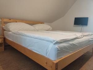 Bett mit weißer Bettwäsche und Kissen in einem Zimmer in der Unterkunft Katerina Vendégház in Tihany