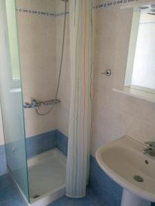 eine Dusche mit Glastür neben einem Waschbecken in der Unterkunft Petalidi Beachview in Petalidi