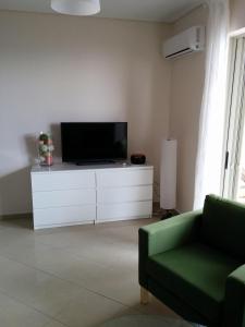 ein Wohnzimmer mit einem TV und einer grünen Couch in der Unterkunft Petalidi Beachview in Petalidi