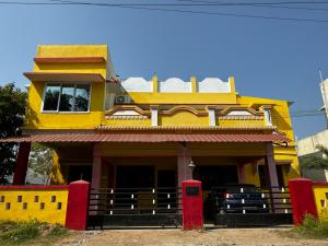 a yellow house with a red gate in front of it at JP HOME STAY in Tiruvannāmalai