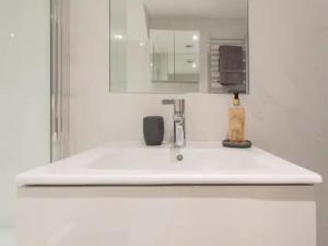 ein weißes Waschbecken im Bad mit Spiegel in der Unterkunft Paddington Apartment 5mins from St Mary Hospital Pass the Keys in London