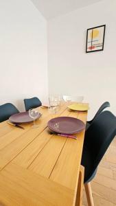 un tavolo in legno con sedie e piatti sopra di Le Salin - Terrasse - Parking - Wifi a Clermont-Ferrand Altre 7 foto