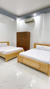 two beds in a room with white walls at Nhà Nghỉ Hạnh Phúc in Vị Thanh