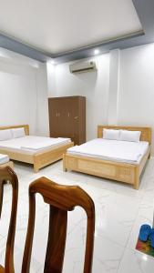 two beds in a room with two chairs at Nhà Nghỉ Hạnh Phúc in Vị Thanh