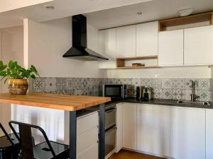 a kitchen with white cabinets and a wooden counter top at Home Chic Home - Les Toits de Sainte-Ursule in Montpellier