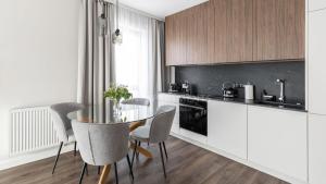 una cucina con armadi bianchi, tavolo e sedie di Lion Apartments - SCALA City Center Apartments&Studio IIA a Danzica