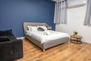 1 dormitorio con 1 cama, 1 sofá y paredes azules en GODSON TALPIOT en Haifa