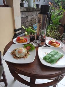 Una mesa de madera con platos de comida encima. en Sastra Ubud House, en Ubud