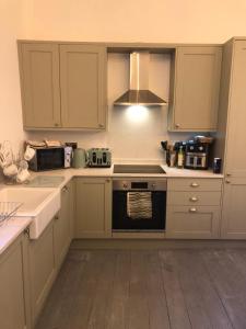 a kitchen with white cabinets and a stove top oven at Compton House 1 in Conwy