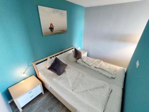 een kleine slaapkamer met een bed en een blauwe muur bij Ferienpark K04-009 Ferienpark in Heiligenhafen