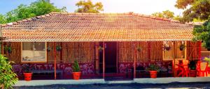 un pequeño edificio con bancos y plantas rojas en VedKasturi Farmstay - Agrotourism, en Giravali