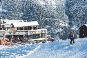 une personne faisant du snowboard sur une piste enneigée dans l'établissement Mountainhotel Saint Roch, à Puy-Saint-Vincent