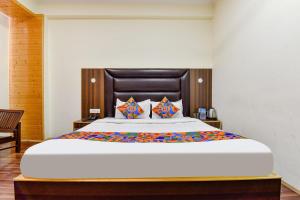 a bedroom with a large bed with a wooden headboard at FabHotel Manali Heaven in Manāli
