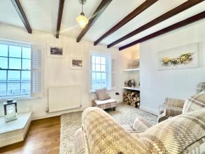 una sala de estar con paredes blancas y techos de madera. en Harbourside, en Staithes