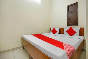 Bett mit roten und weißen Kissen in einem Zimmer in der Unterkunft Wave Inn Guest House in Ludhiana