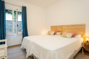 a bedroom with a large white bed with blue curtains at Villa Arena in Es Mercadal