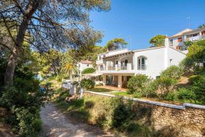 a white house with a stone wall and trees at Villa Arena in Es Mercadal