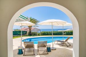 a view of a swimming pool with chairs and umbrellas at Villa Mila in Sant Lluis