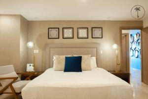 a bedroom with a large white bed with a blue pillow at Stylish Apt. w/ Rooftop, Infinity Pool & Sea View in Mazatlán +22 photos