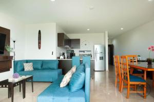 a living room with a blue couch and a kitchen at Spacious Apartment with Private Balcony & Ocean View - Brujas in Mazatlán