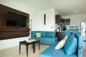 ein Wohnzimmer mit einem blauen Sofa und einem Tisch in der Unterkunft Spacious Apartment with Private Balcony & Ocean View - Brujas in La Florida