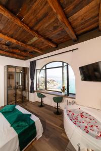 1 dormitorio con bañera, cama y ventana en Kemì Luxury Suites en Vietri
