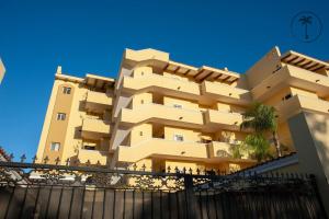 ein hohes gelbes Gebäude mit einem Zaun davor in der Unterkunft Spacious Apartment with Pool Facing the Ocean in Mazatlán - Marina in San Rafael