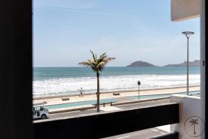 a view of a beach with a palm tree and the ocean at 2 BDR Apartment with Ocean View in Avenida del Mar in Mazatlán
