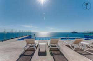 a group of chairs sitting next to a swimming pool at Hermosa Vista al Mar, Condominio de Lujo! in Mazatlán
