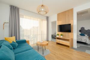 uma sala de estar com um sofá azul e uma televisão em Marynarska Modern Apartment with Parking by Renters em Sarbinowo