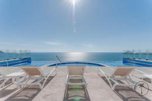 マサトランにあるHermosa terraza con vista a la laguna!のスイミングプールの横に座る椅子