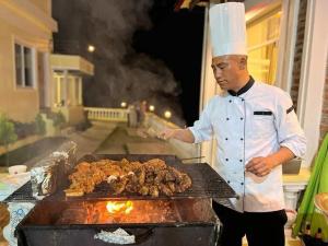 a chef is cooking meat on a grill at ROYAL VILLA RESORT in Kathmandu