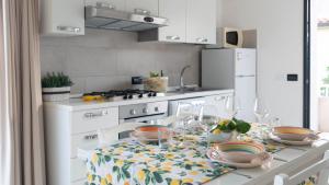 una cocina blanca con una mesa con platos. en Welcomely - La Casa Sul Mare, en Cala Liberotto