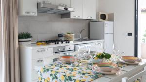 a white kitchen with a table with dishes on it at La Casa Sul Mare in Cala Liberotto